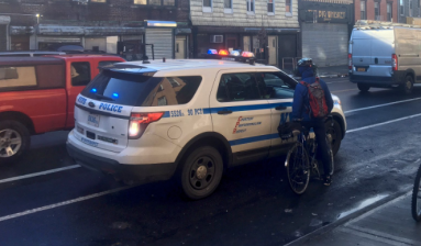 An officer pulling over a cyclist on Grand Street.