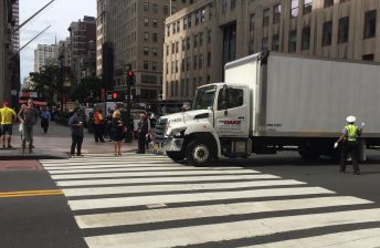 An NYPD traffic control agent directs a commercial truck driver into the eastbound bus lane on 34th Street at Fifth Avenue this morning. Photo: David Meyer