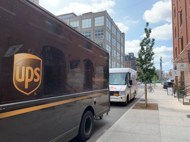 These trucks are parked on what is supposed to be a protected bike lane on West Street in Greenpoint. If they get a ticket, they pay far less thanks to a city program. Photo: Jon Orcutt