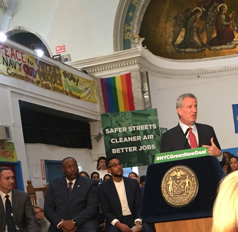 Mayor de Blasio, with the angels of El Puente above him, speaks to reporters. Photo: Gersh Kuntzman