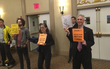 Safe-streets activists hold signs at Community Board 7's meeting. Andrew Rosenthal is at right. Photo: Eve Kessler