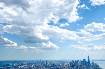 A photo of the Manhattan skyline with lots of fluffy clouds and blue sky.