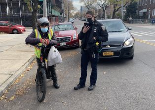 SAY CHEESE: Officer Jessica Ricotta of the 114th Precinct writing a ticket to an e-bike delivery worker for following the LPI. Photo: Twitter