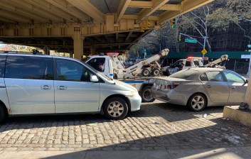 An NYPD tow truck latches onto an illegal parker on a sidewalk under the BQE at Navy and Tillary streets in Downtown Brooklyn. Photo: Council Member Steve Levin (no, really)