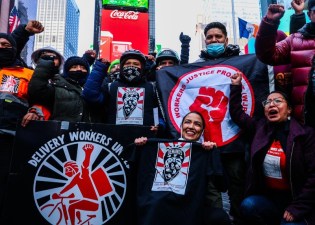 Rep. Alexandria Ocasio-Cortez (front row, right) joined hundreds of delivery workers in a rally in Times Square on Sunday, one day before reforms passed last year go into effect. Sen. Chuck Schumer was also there. Photo: Adrian Childress