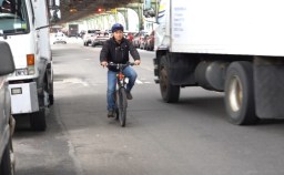 A delivery worker on an e-bike maneuvers around a truck. File photo