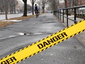 A cyclist heads towards Ocean Parkway's cracked pavement, which has spread north of Avenue R. We added "Danger" tape to make it more dramatic. Photo: Jon Orcutt