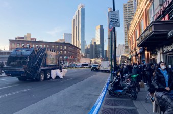 The garbage truck was still at the intersection an hour after the crash at Atlantic and Flatbush avenues, a sheet covering the victim's gruesome injuries. Photo: Julianne Cuba