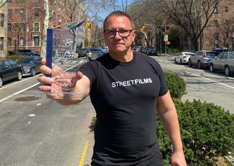 Clarence Eckerson Jr. on the 34th Avenue open street with his award from the United Freakin' Nations.