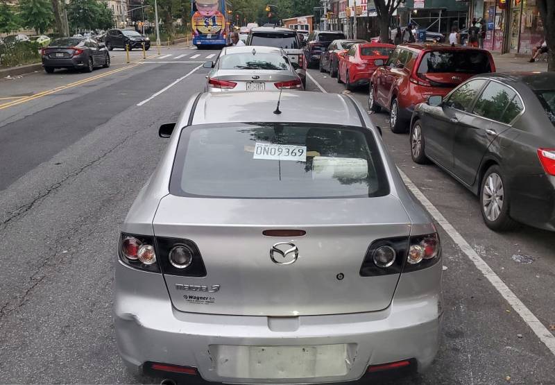 A line of unticketed cars parking in the bike lane in Upper Manhattan.