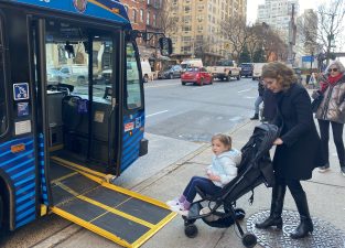 Council Member Julie Menin pushes her daughter Maddie, 4, onto a bus on the Upper East Side. Photo: Kevin Duggan