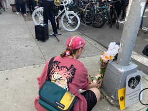 Frederique Uster-Hug lays flowers down for her husband Adam Uster, who was killed on May 1 by a truck driver at the corner of Franklin and Lexington Avenues. Photo: Julianne Cuba